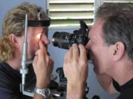 Iridologist with a head torch lighting the subject's eye while a photographer captures it through a DSLR